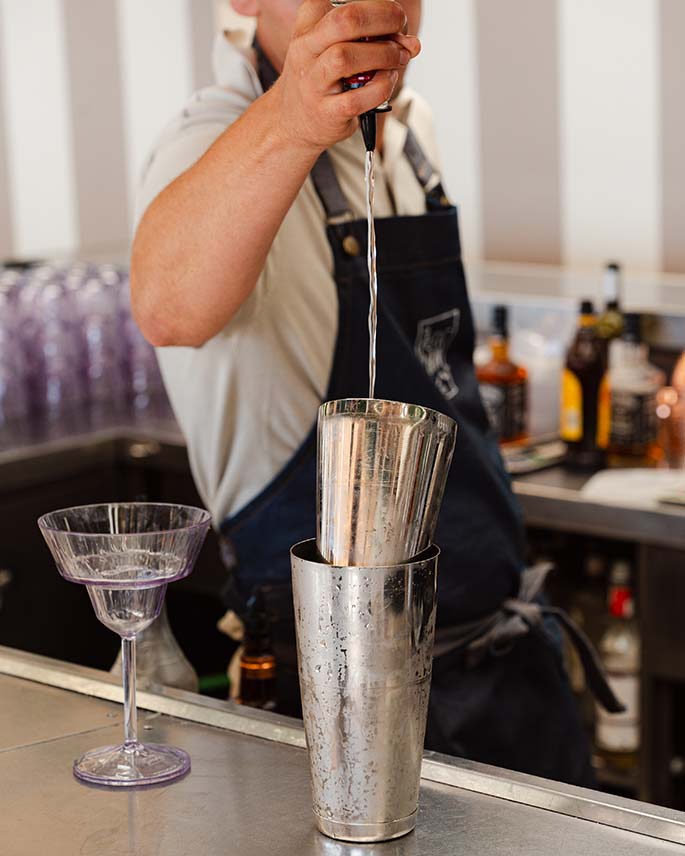 Barman préparant un cocktail signature au restaurant de plage Le Petit Bain à Hyères