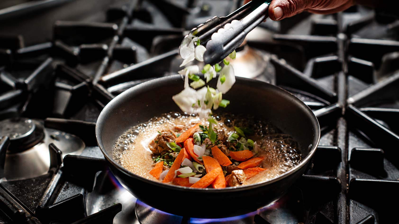 Préparation d'un plat à la poêle dans les cuisines du restaurant Le Petit Bain à Hyères