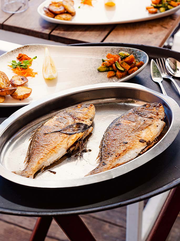Poisson d'arrivage grillé d'environ 500 g servi avec pommes grenaille et légumes au restaurant Le Petit Bain à Hyères